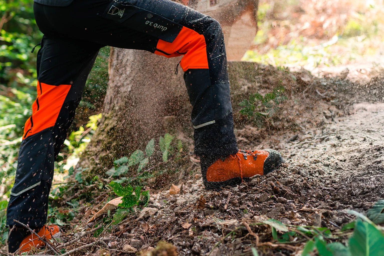 Jambes d’une personne portant un pantalon de protection et des chaussures de s�curit� lors de travaux forestiers, des copeaux de bois volent